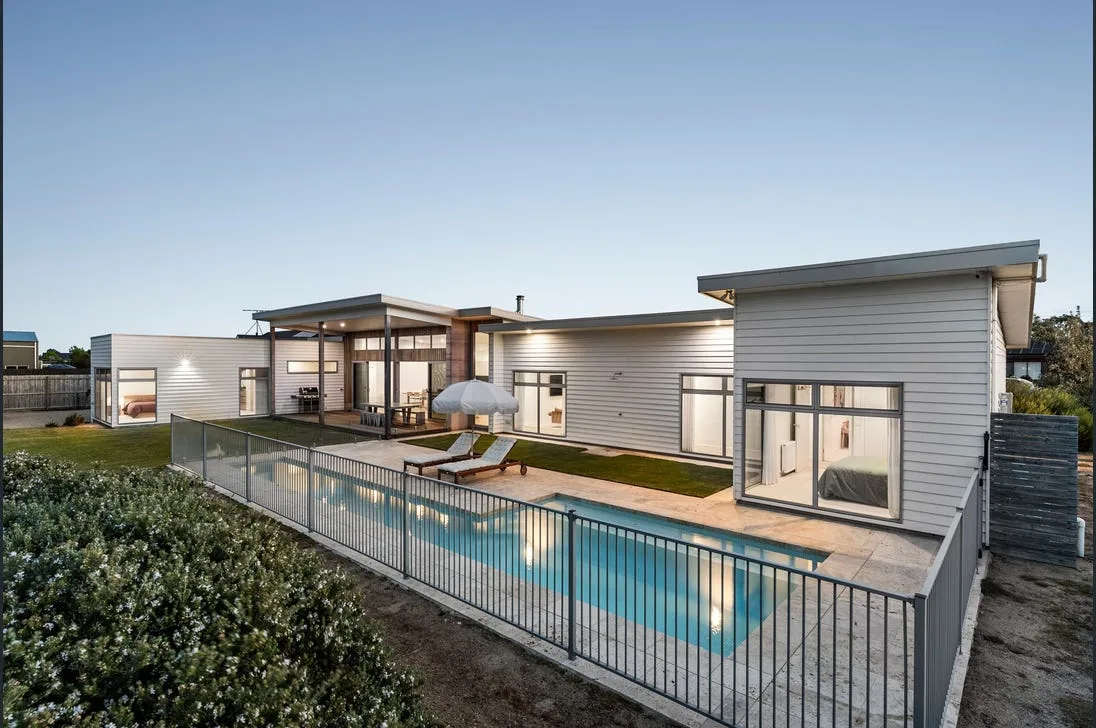 Black aluminium pool fencing around a pool beside a modern home