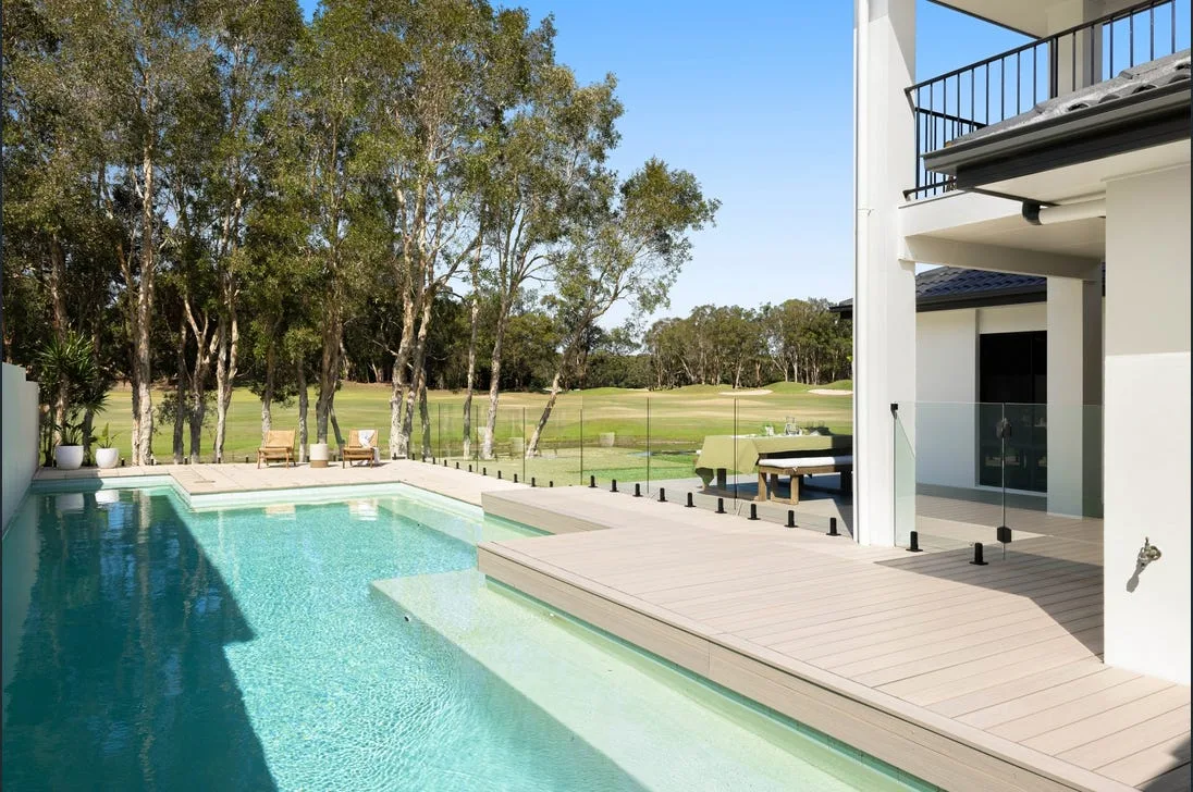 Frameless glass fencing beside a pool and timber deck at a modern home