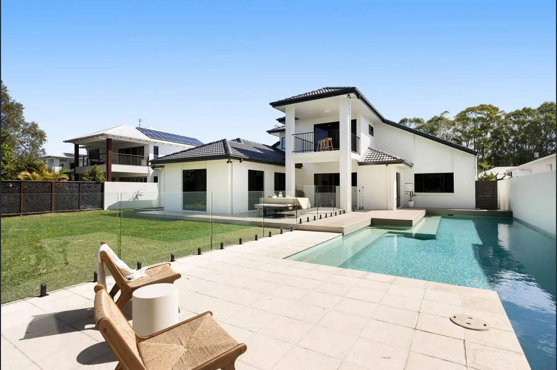 Frameless glass pool fence with outdoor chairs on a paved pool surround