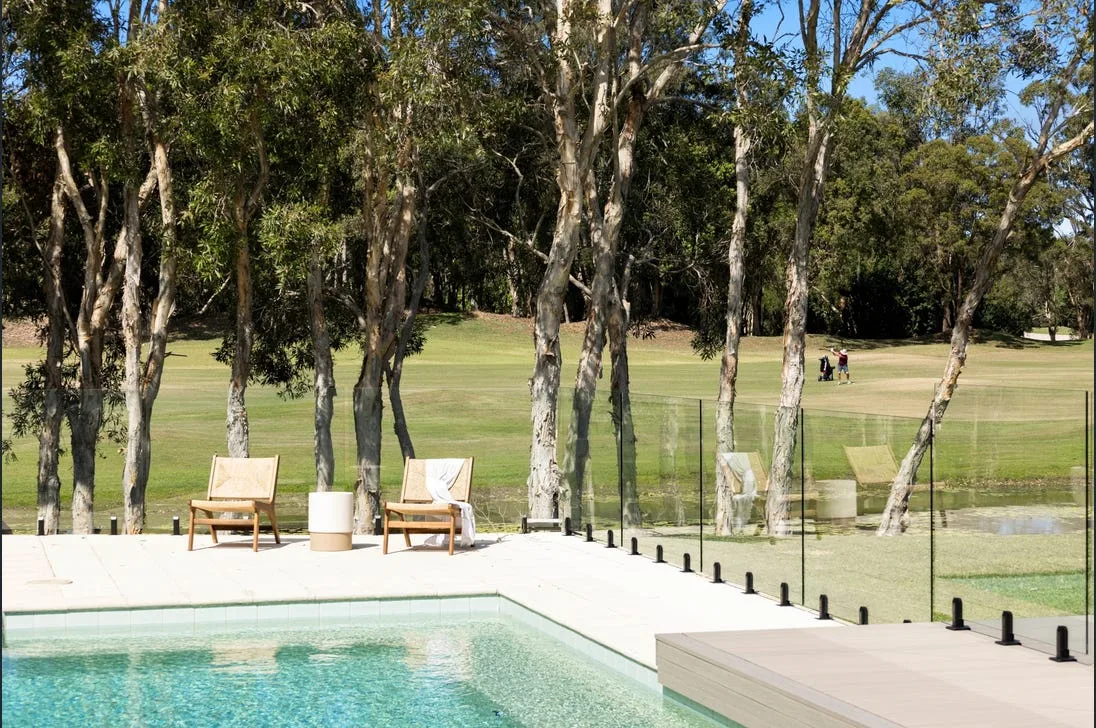 Frameless glass pool fence with a golf course view behind it