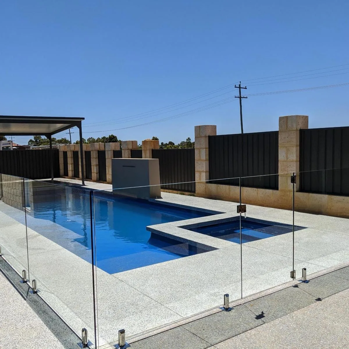 Frameless glass pool fence on spigots around a lap pool and spa