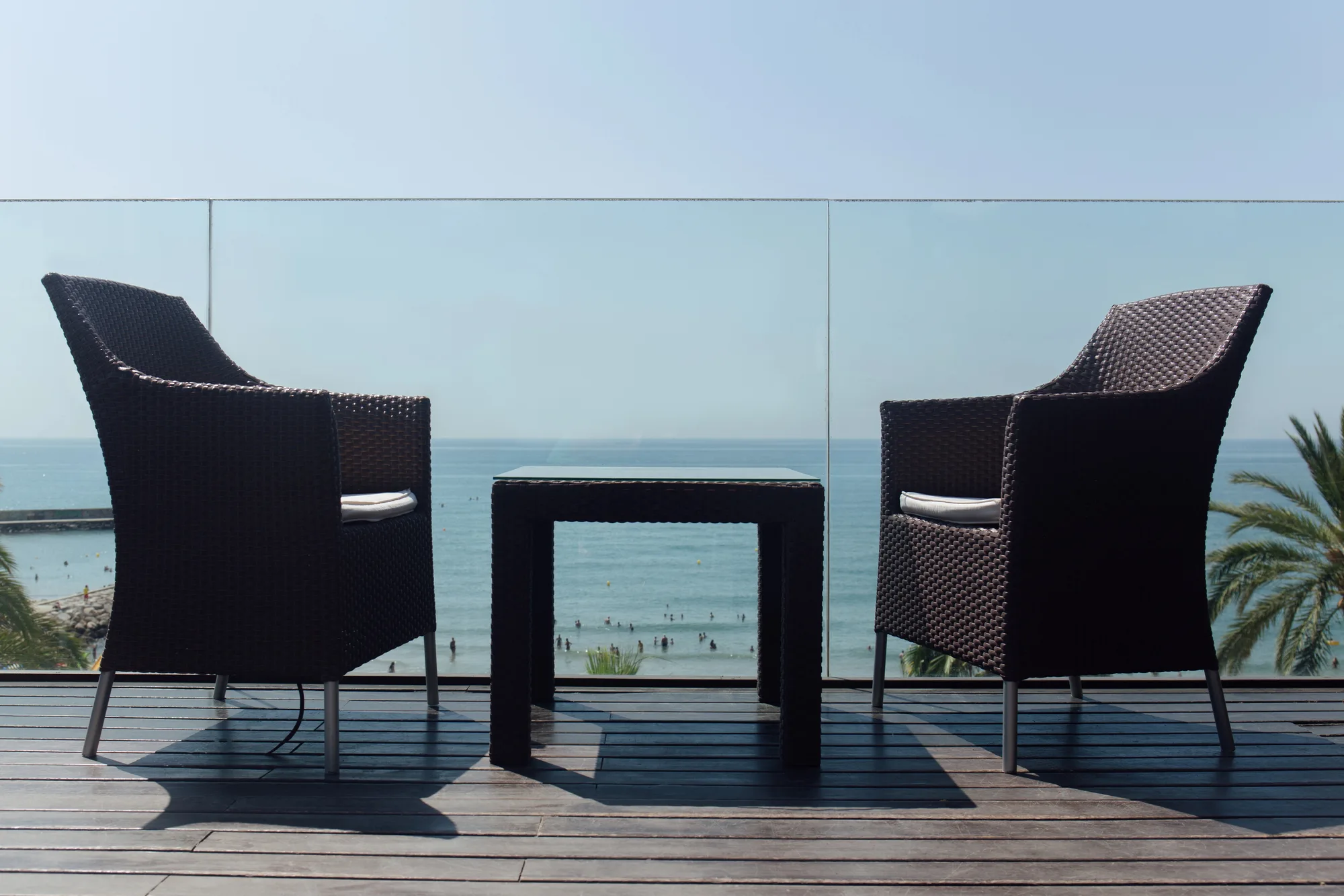 Glass balustrade on an ocean-view deck with outdoor chairs