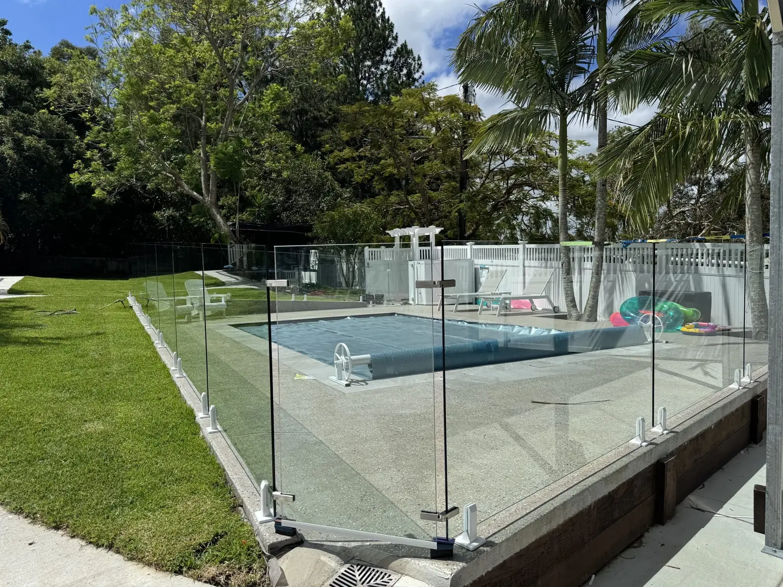 Frameless glass pool fence installed on a timber-edged pool surround