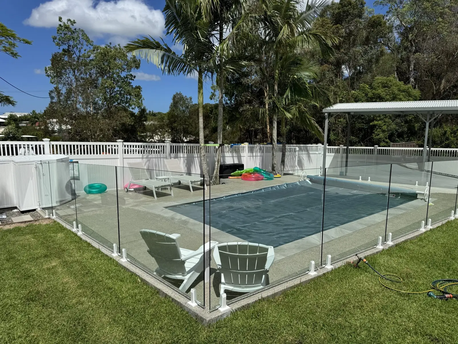 Frameless glass pool fence enclosing a backyard pool and lawn