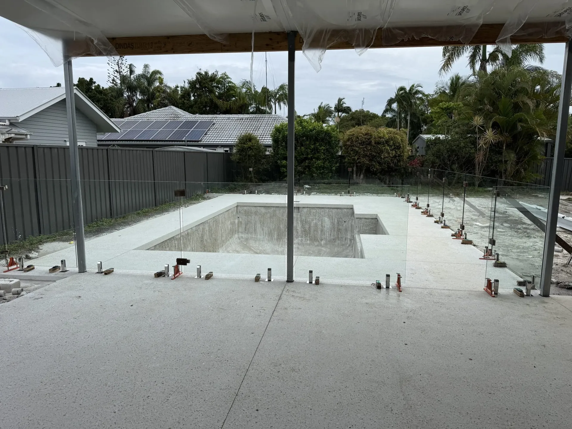 Glass pool fence installation around a new pool beside a covered patio