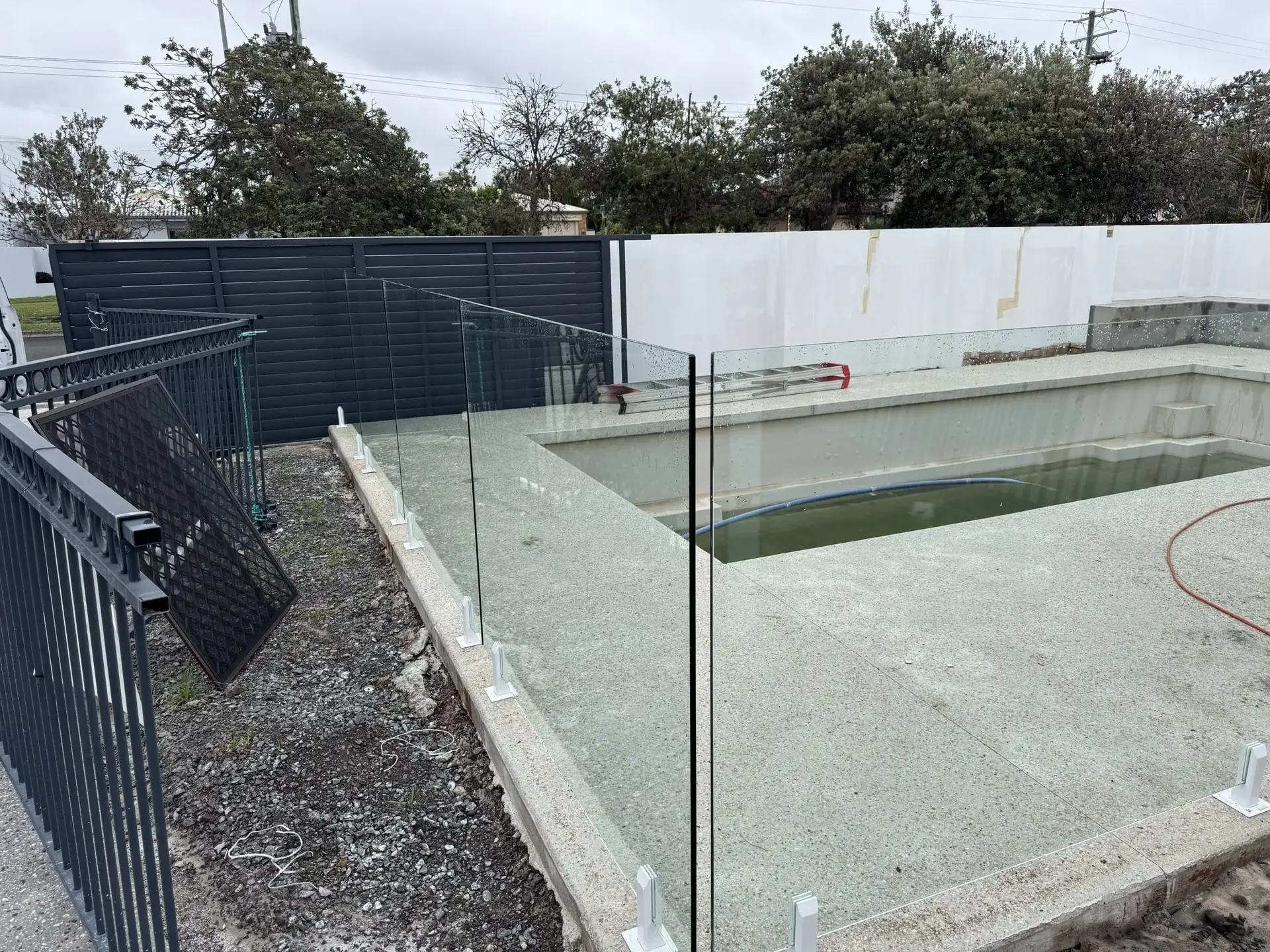 Glass pool fence beside an aluminium side gate during installation