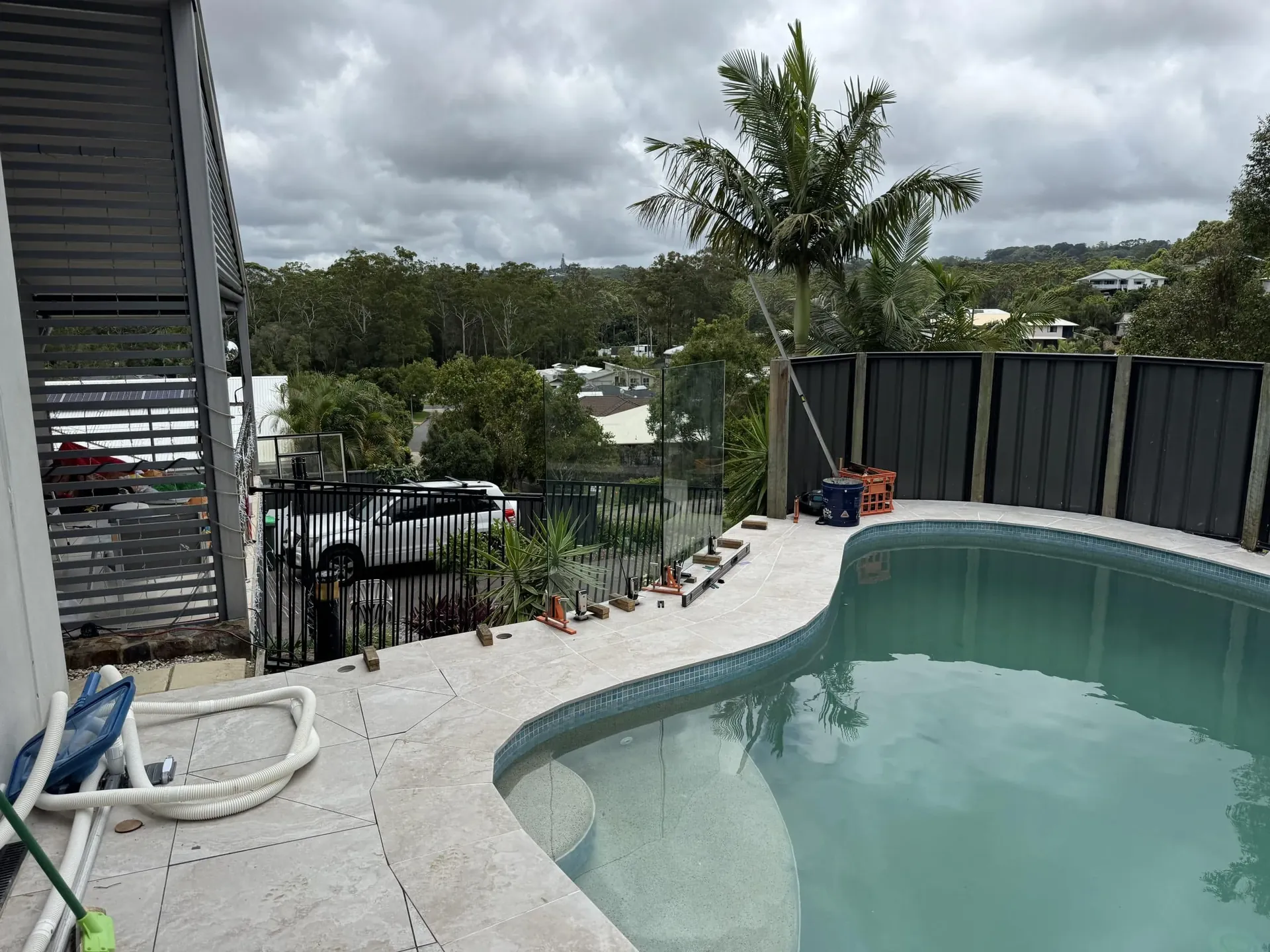 Glass pool fence beside a curved pool with hinterland views