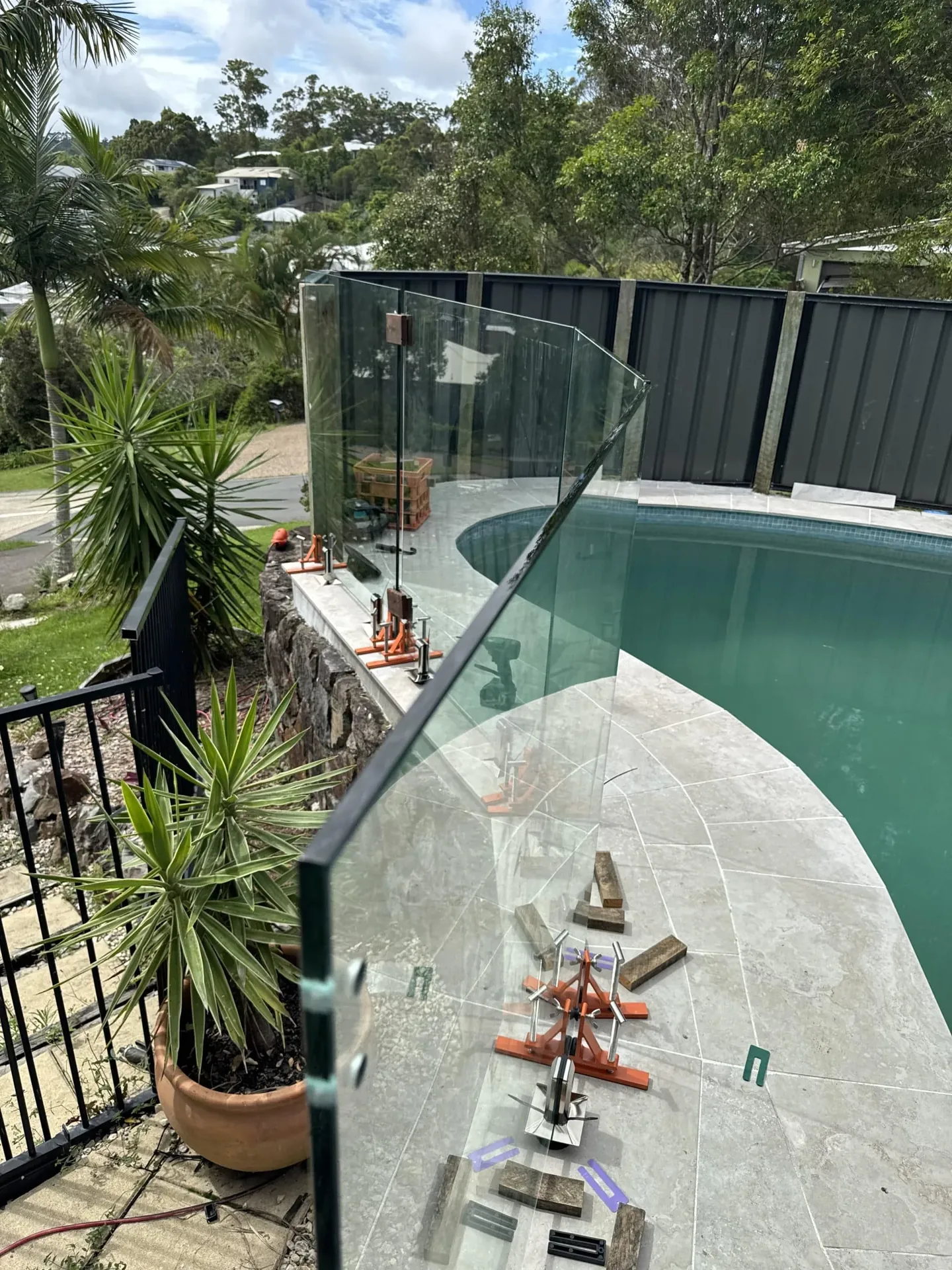 Curved pool edge with a frameless glass fence panel