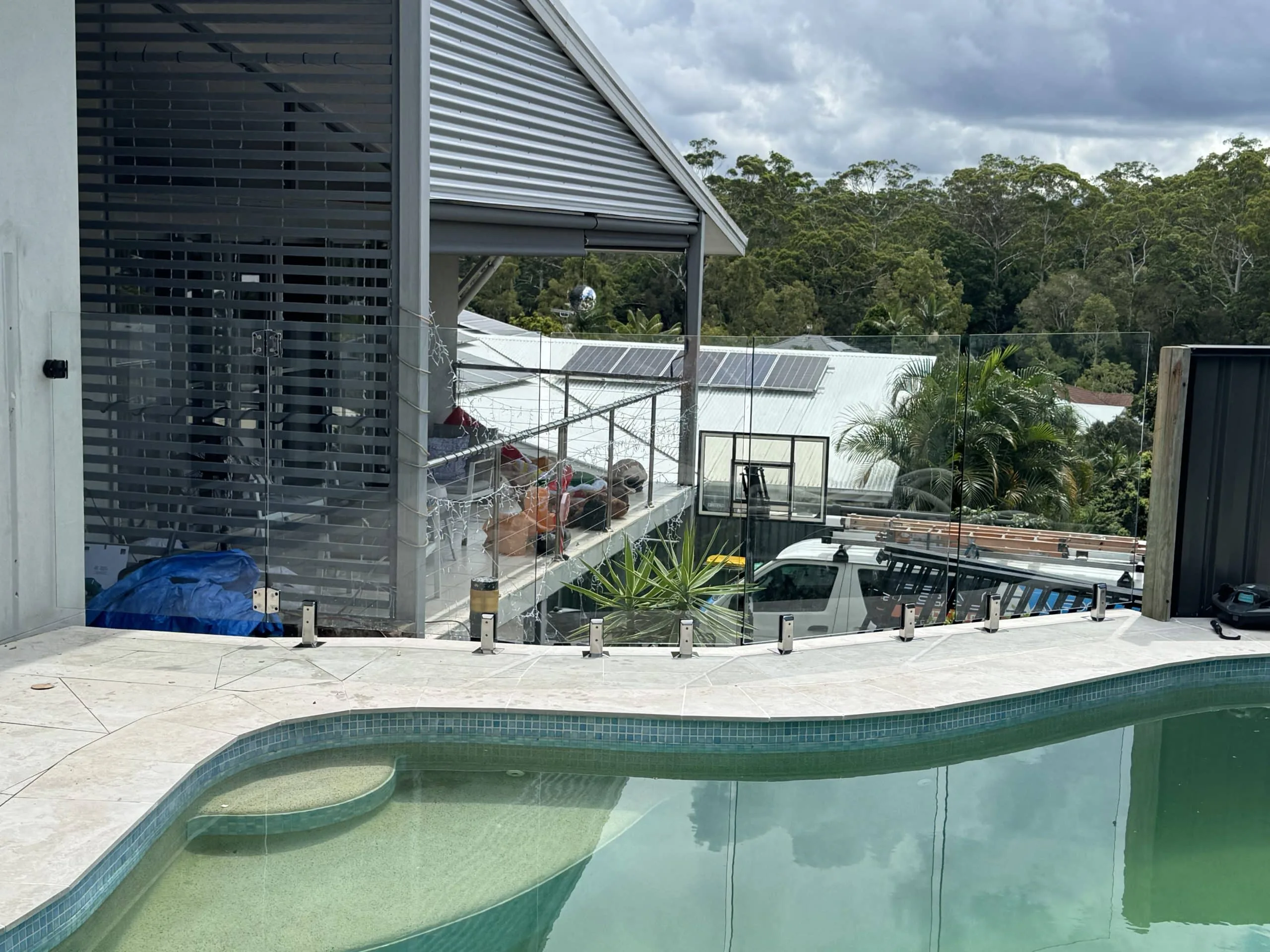Glass pool fencing around a freeform pool beside a house