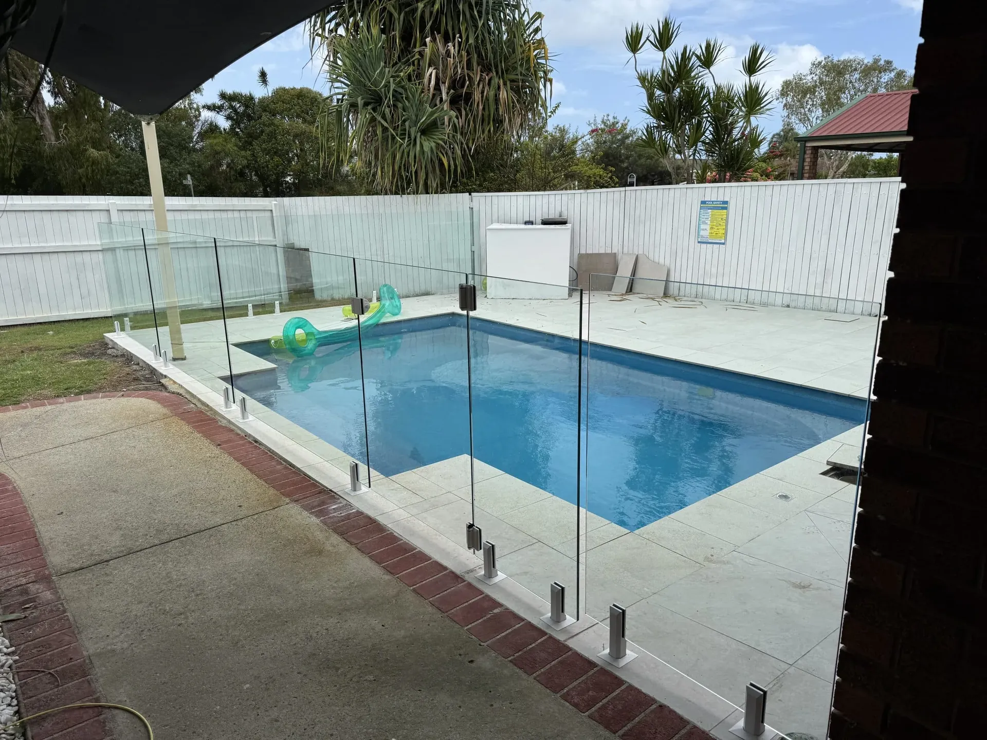 Frameless glass pool fence corner on a paved pool surround