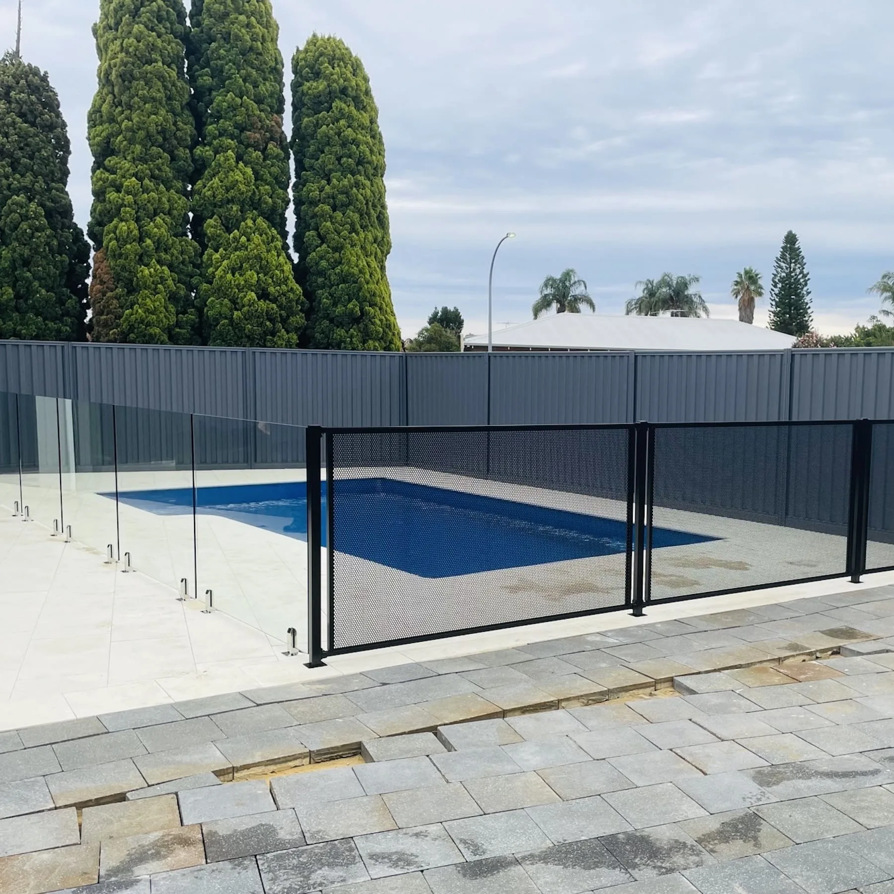 Black mesh pool fence around a pool on a stone patio